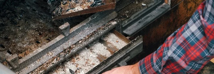 Person reinigt Asche aus Ofen